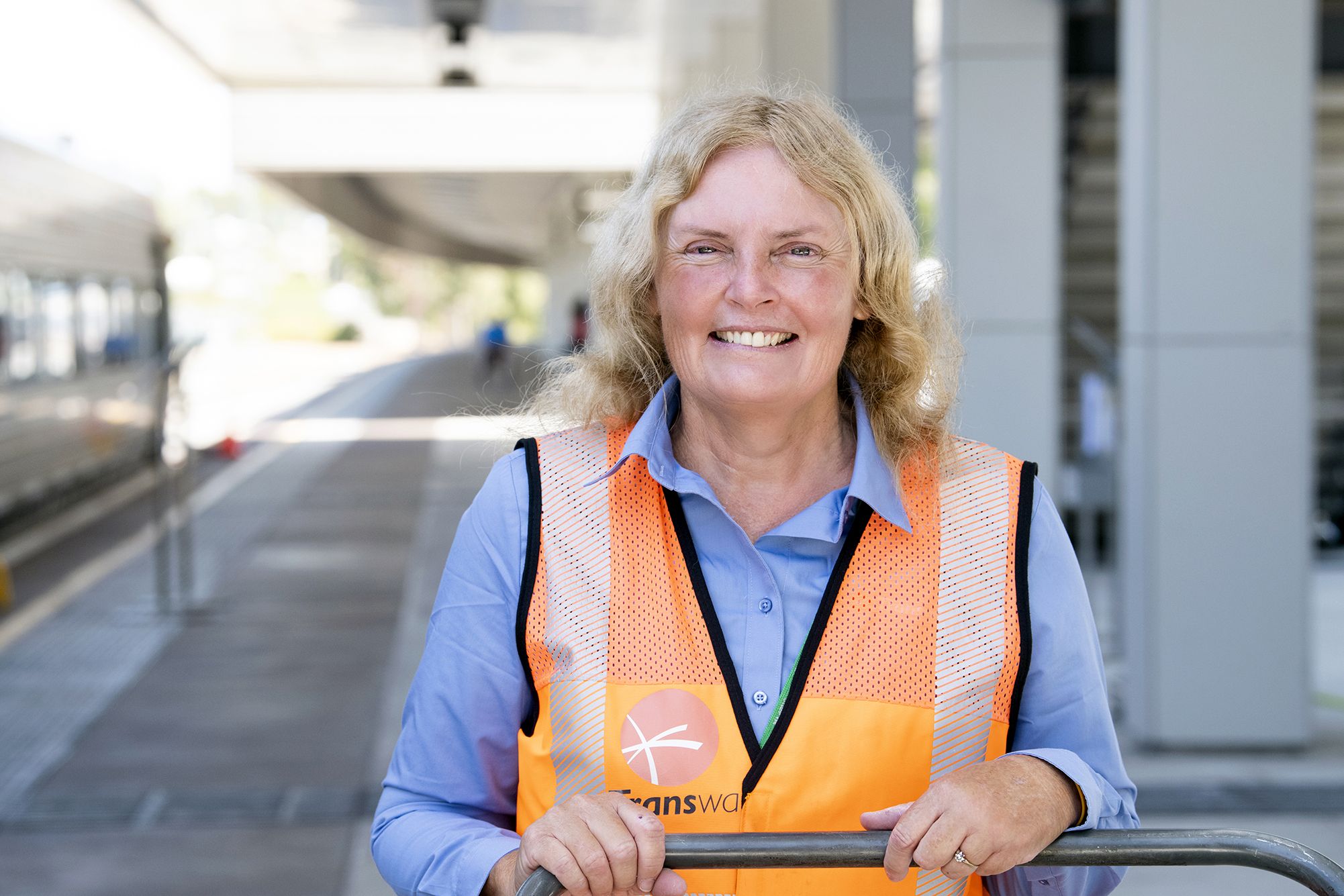 Sharon smiling in high-vis jacket at a train station