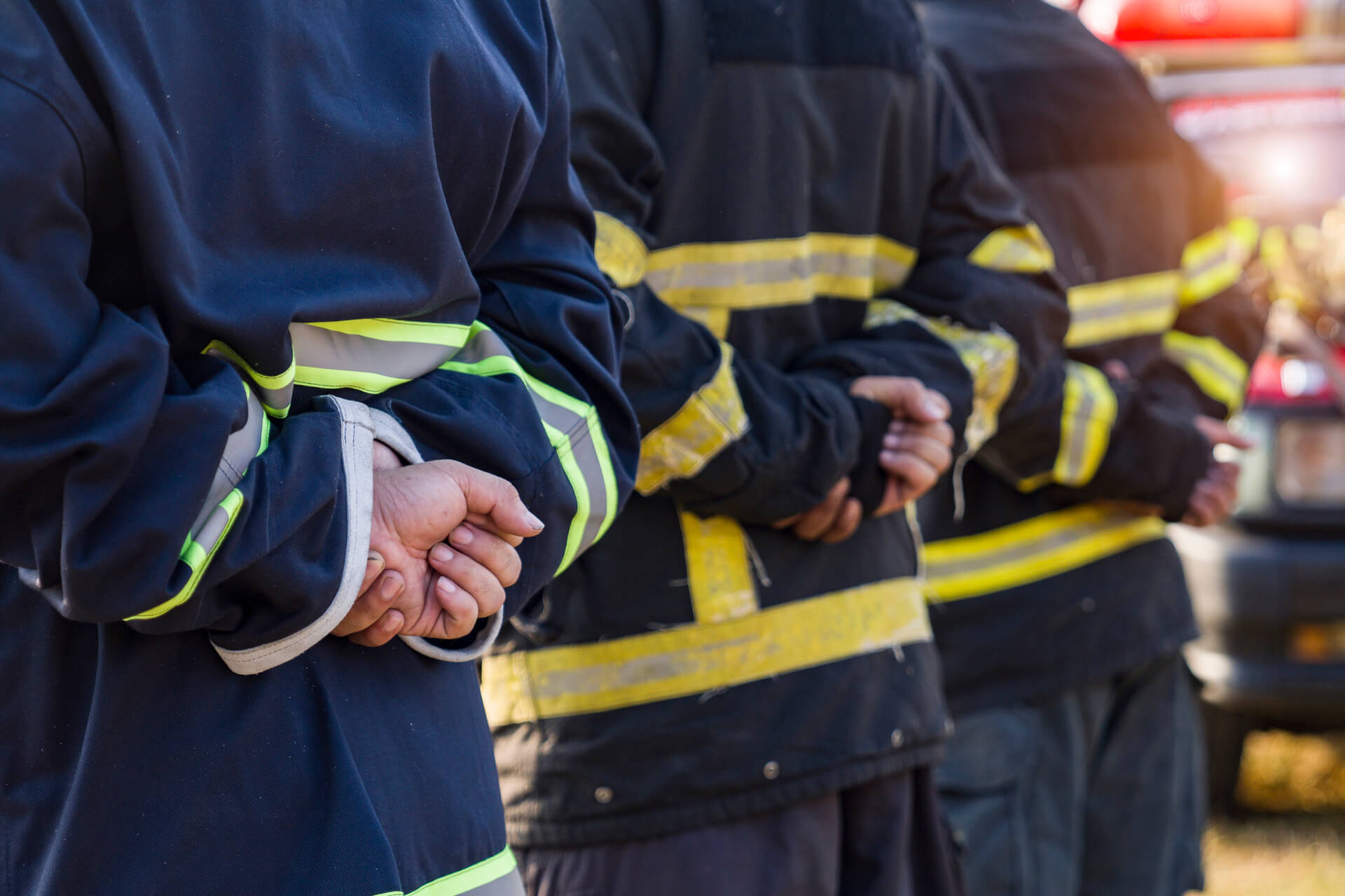 Firefighters standing in front of a car, ready to respond to an emergency situation.