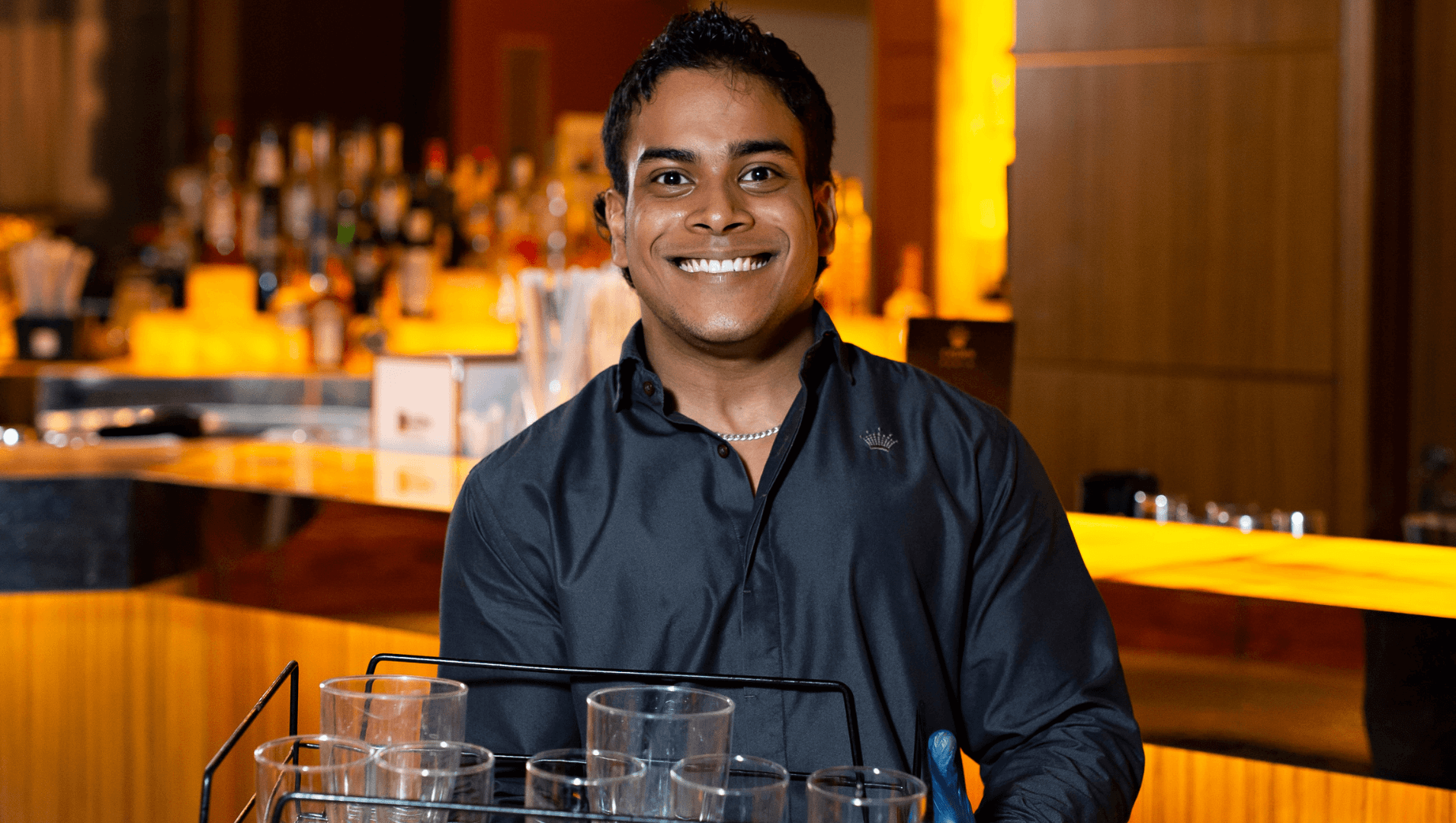 DES participant Clyde smiles while holding a tray behind a bar