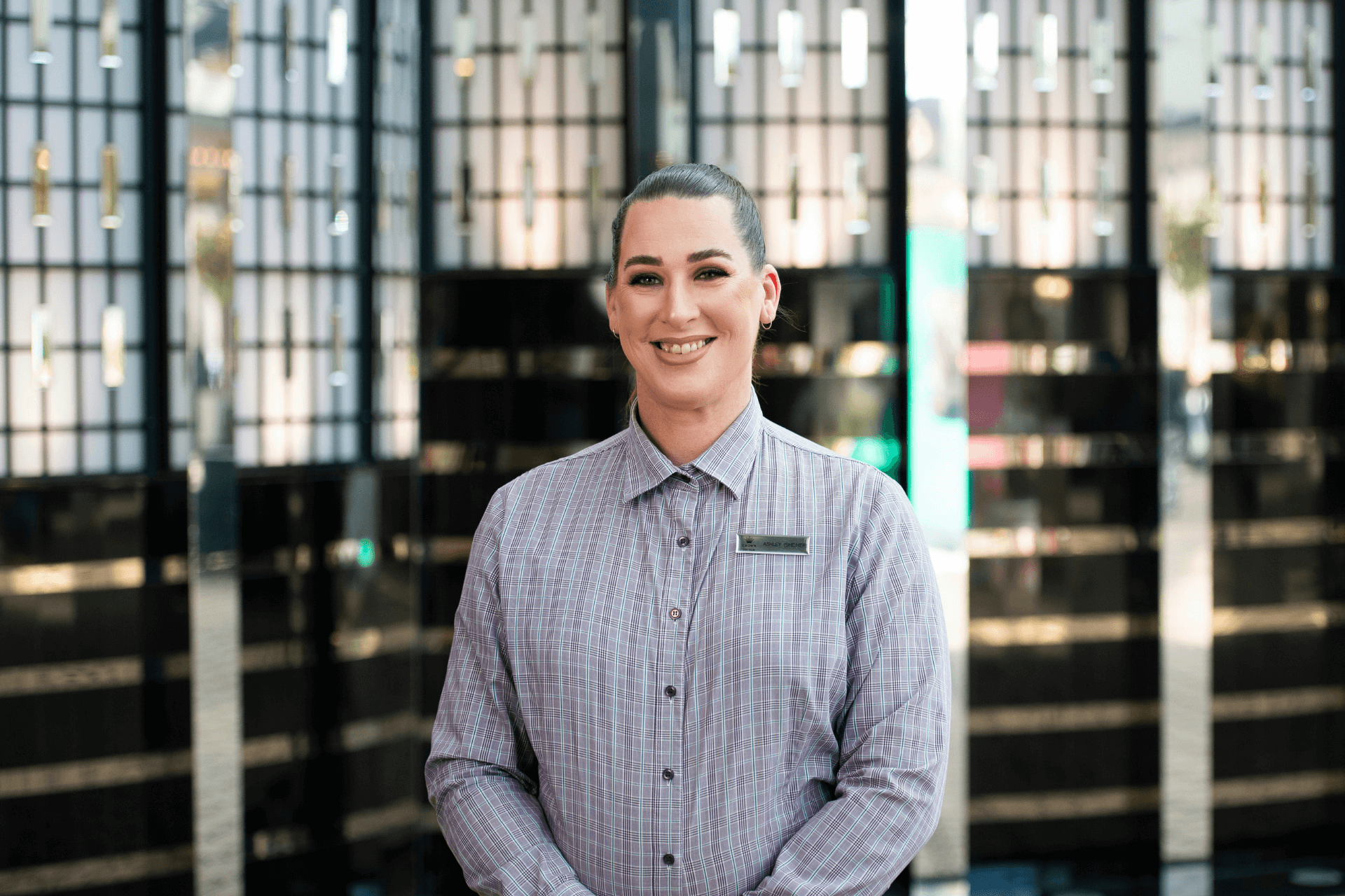 Ashley smiles in uniform and a name tag in the hotel foyet