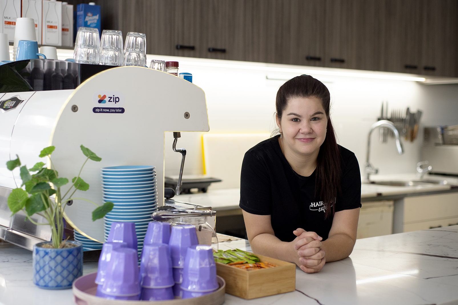 DES participant Jess leaning on the counter of a cafe 