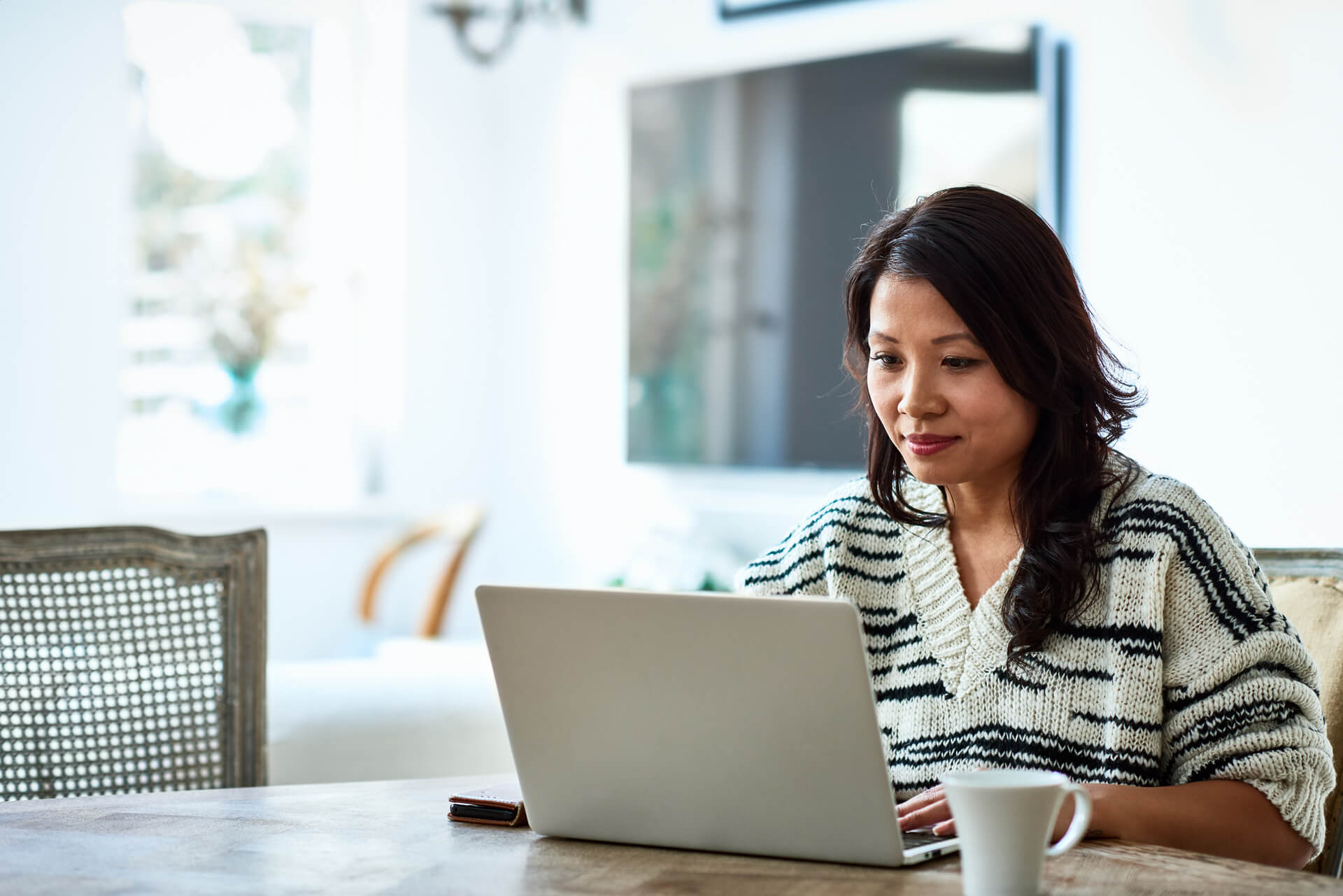 A woman sits at a table with a laptop