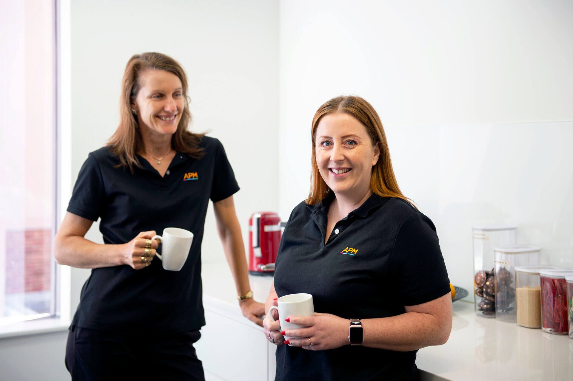 two APM employees discussing over coffee